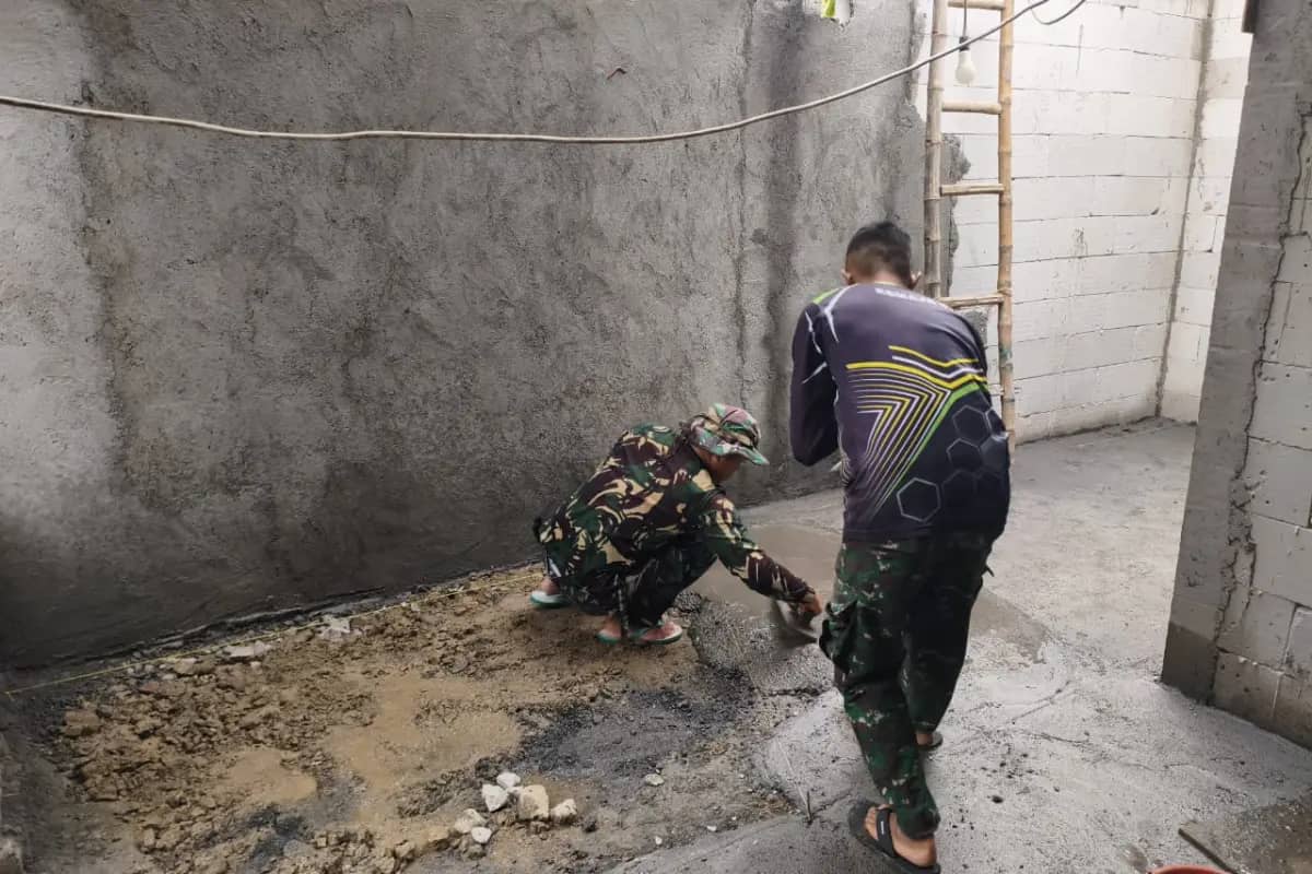 Gotong Royong Satgas TMMD 128 Gresik dan Warga Ratakan Lantai Rumah Ibu Eka